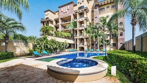 Un hotel con piscina, palmeras y jacuzzi.