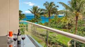 A balcony with a clear view of the ocean and palm trees.