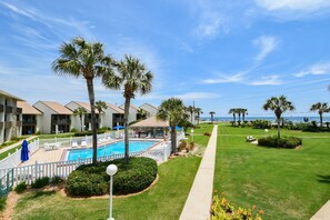 A hotel with a swimming pool, palm trees, and a view of the ocean.
