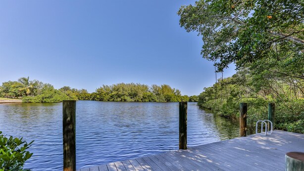 A wooden dock extending into calm water, surrounded by lush greenery and trees. - LAKE PALMS 1 - Sanibel Condo Overlooking Lagoon (Sanibel)