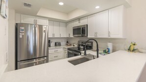 A modern kitchen with white cabinets, stainless steel appliances, and a central island. - LAKE PALMS 1 - Sanibel Condo Overlooking Lagoon (Sanibel)