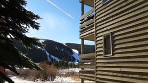 Une cabane en bois dotée d’un balcon donnant sur un paysage enneigé et des montagnes.