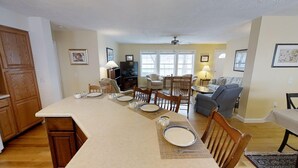 A spacious living room with a large dining table, a television, and a sofa.