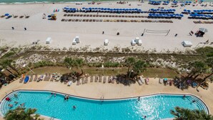 Ein Strand mit Schwimmbad, Liegestühlen und Sonnenschirmen.