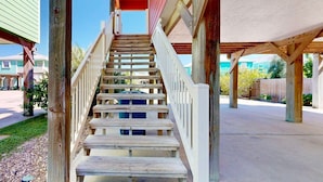 A wooden staircase leading to a covered porch area with a view of a residential street. - Parking for Boat, Shared Pool, Outdoor Seating Areas, Pet Friendly (Port Aransas)