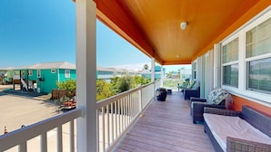 A covered porch with outdoor seating, a view of neighboring houses, and a clear sky. - Parking for Boat, Shared Pool, Outdoor Seating Areas, Pet Friendly (Port Aransas)