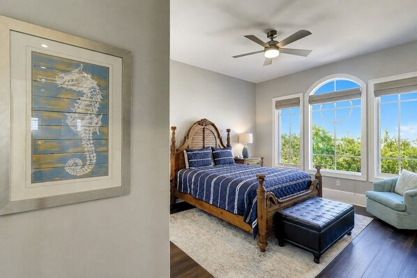 A bedroom with a large bed, a ceiling fan, and a window with a view of greenery. - 33 Dune Lane- Oceanfront & Beautiful! (Hilton Head Island)