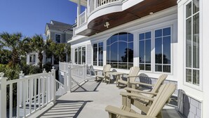 A white building with a balcony, large windows, and outdoor seating. - 33 Dune Lane- Oceanfront & Beautiful! (Hilton Head Island)