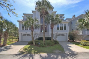 A two-story house with a symmetrical facade, a central entrance, and a well-maintained front yard with palm trees and shrubs. - 33 Dune Lane- Oceanfront & Beautiful! (Hilton Head Island)