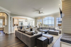 A spacious living area with a large sectional sofa, a dining area, and a kitchen. - 33 Dune Lane- Oceanfront & Beautiful! (Hilton Head Island)