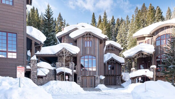 A large, multi-story lodge with a snow-covered roof and stone exterior.