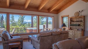 A cozy living room with large windows, a wooden ceiling, and a view of the outdoors. - Bright lakeview home near Tahoe City, huge sunny lakeview deck (Tahoe City)