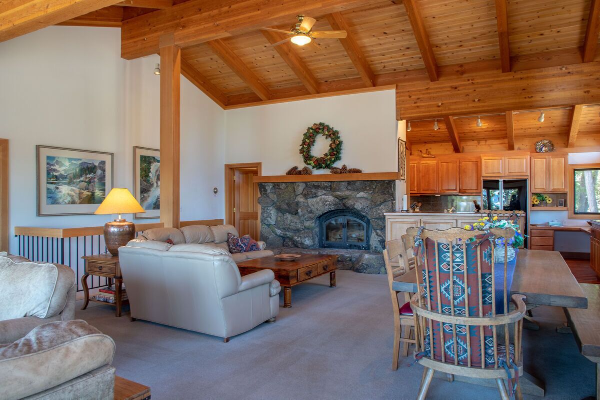 A cozy living room with a fireplace, wooden ceiling beams, and a stone fireplace surround.