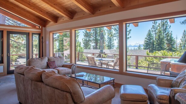 A spacious living area with a large window overlooking a deck and a hot tub. - Bright lakeview home near Tahoe City, huge sunny lakeview deck (Tahoe City)