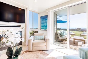 Una sala de estar con televisor, sofá, mesa de centro y vistas al exterior.