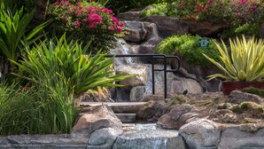 A small waterfall in a garden with a sign that says "Please don't climb rocks."