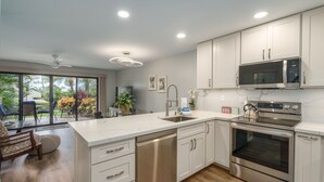 A modern kitchen with white cabinets, stainless steel appliances, and a large island.