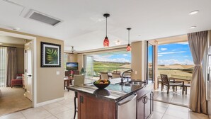 Uma cozinha moderna com uma ilha central, uma área de jantar com vista e uma sala de estar com televisão.