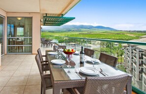 A dining area with a table set for four, overlooking a scenic landscape with mountains and a valley.