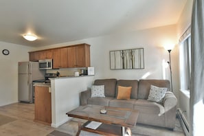 A compact living space with a kitchenette, a sofa set, and a coffee table.