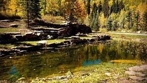 A natural landscape with a clear pond surrounded by autumn-colored trees and rocky terrain. - Rustic & Spacious Log Cabin w/Private Hot Tub, Amazing Views, 4 Miles to Ski (Durango)
