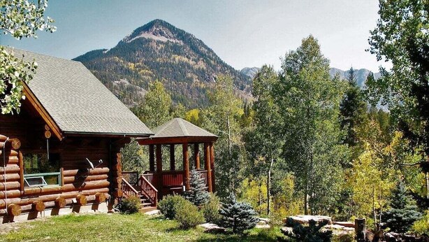 A log cabin with a porch and a gazebo, surrounded by a forested landscape and mountains in the background. - Rustic & Spacious Log Cabin w/Private Hot Tub, Amazing Views, 4 Miles to Ski (Durango)