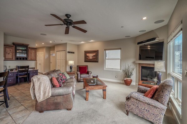 A spacious living room with a fireplace, a ceiling fan, and a large window. - River Aerie-Relax by the River (Salida)
