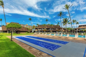Ein Poolbereich mit Shuffleboard, Liegestühlen und Palmen.