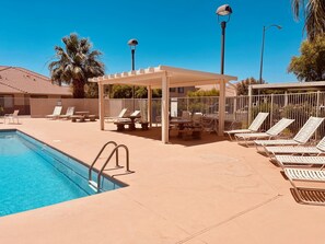 Relax by the rectangular pool surrounded by lounge chairs and sunbeds under a covered pavilion.