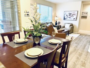 Enjoy meals in this inviting dining area with a table for four, comfortable seating, and a potted plant.