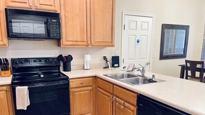 A kitchen with wooden cabinets, a black stove, a microwave, a dishwasher, and a sink.