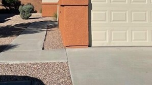 A residential house with a garage, a light fixture, and a landscaped driveway.