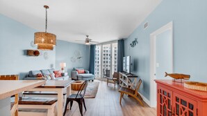 Ein geräumiges Wohnzimmer mit Essbereich, Fernseher und Blick auf die Stadt durch große Fenster.