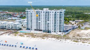 A high-rise hotel with multiple floors, a swimming pool, and a beach area.