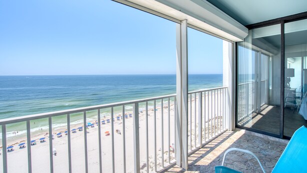 A balcony with a view of the beach and ocean.