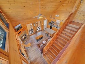 A wooden cabin interior with a living area, kitchen, and a staircase. - Private Hot Tub | Seclusion | Pool Table | Pet Friendly (SEVIERVILLE)