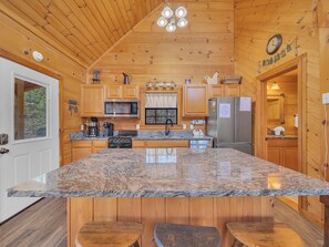 A kitchen with wooden cabinets, a granite countertop, stainless steel appliances, and a wooden ceiling.