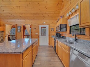 A kitchen with wooden cabinets, granite countertops, stainless steel appliances, and a view through the window. - Private Hot Tub | Seclusion | Pool Table | Pet Friendly (SEVIERVILLE)