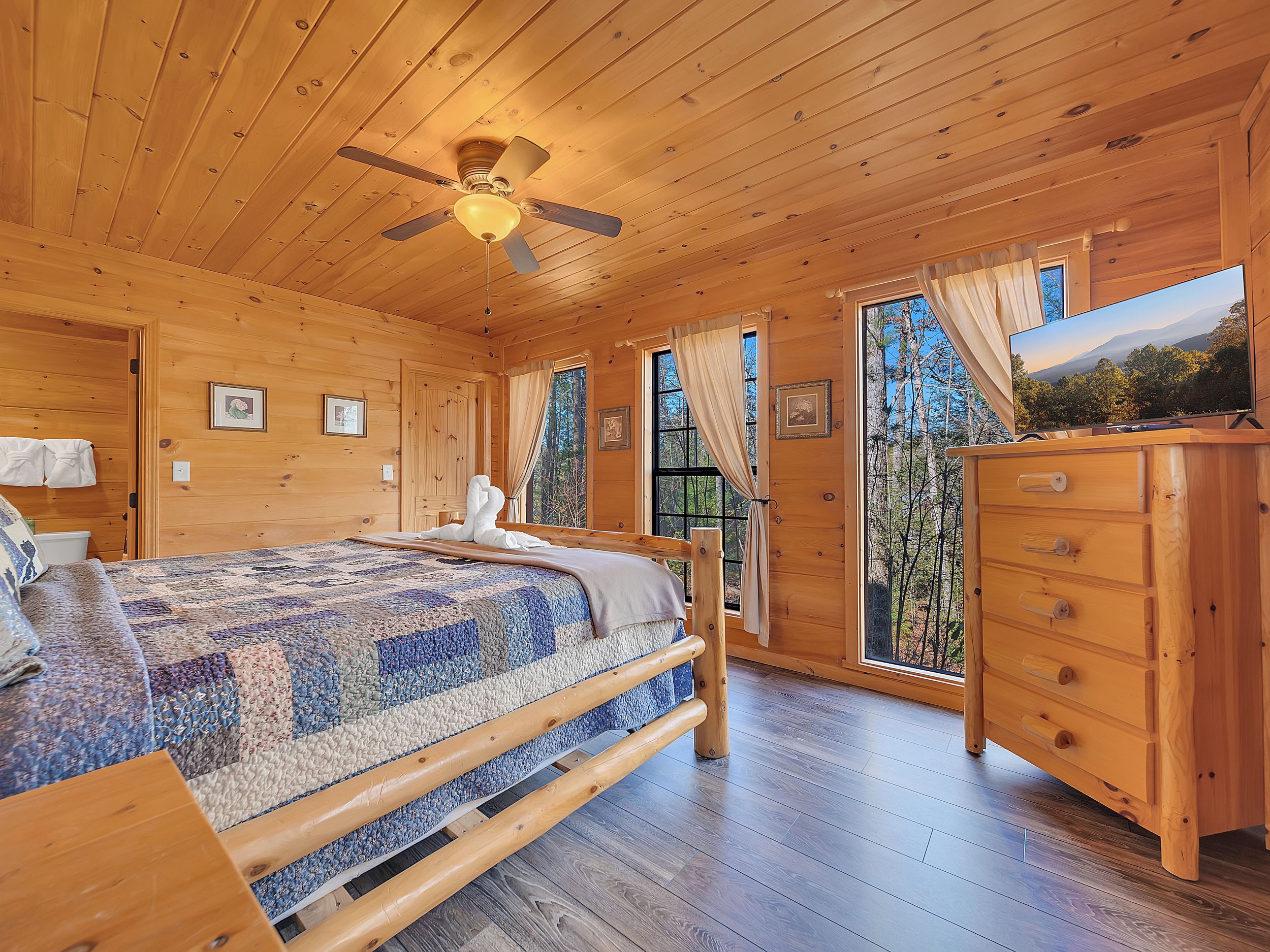 Ein Schlafzimmer einer Holzhütte mit Bett, Schminktisch und Deckenventilator.