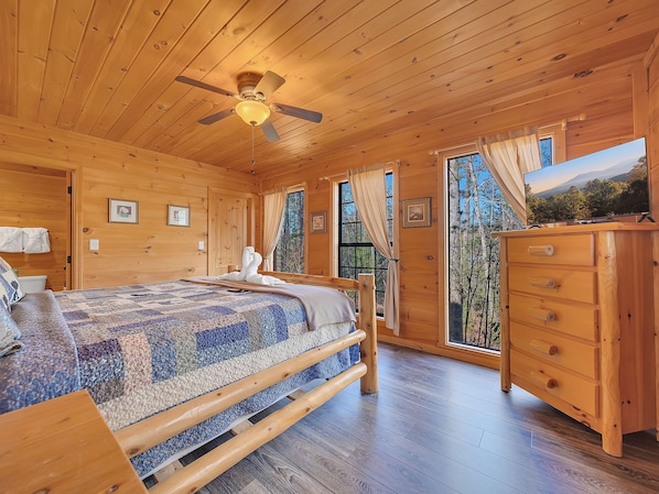 A wooden cabin bedroom with a bed, dresser, and a ceiling fan. - Private Hot Tub | Seclusion | Pool Table | Pet Friendly (SEVIERVILLE)