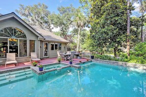 Ein Haus mit Pool, Terrassenmöbeln und Blick auf Bäume.