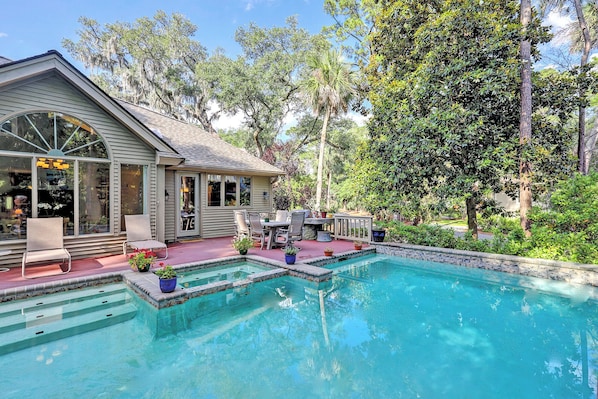 A house with a pool, patio furniture, and a view of trees. - 12 Snowy Egret-4th Row Ocean, Large Pool & Lush setting. (Hilton Head Island)