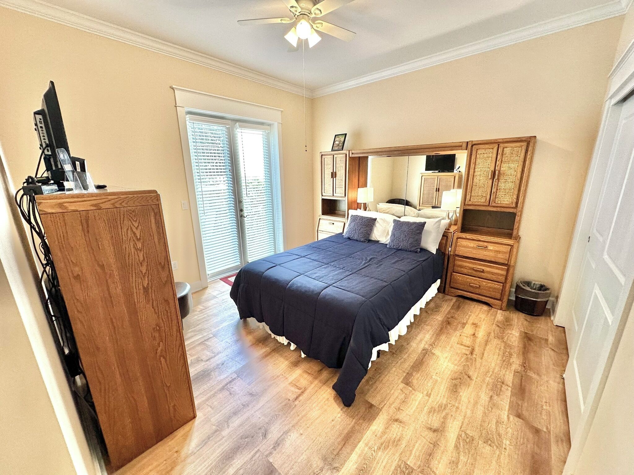 A bedroom with a bed, wooden dresser, and a ceiling fan.