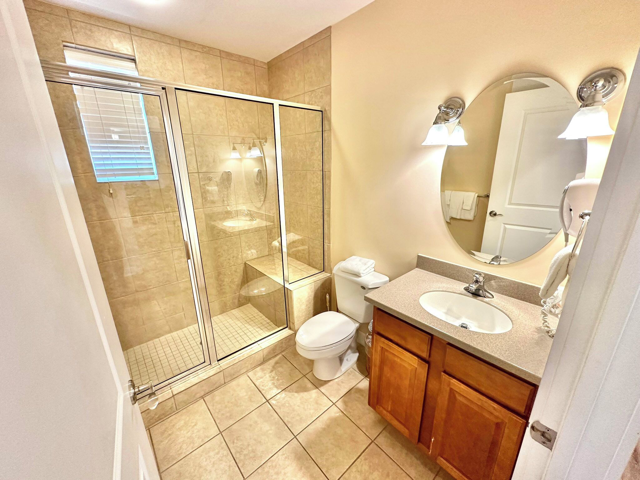 Een badkamer met een douchecabine van glas, een toilet, een wastafel en houten kasten.