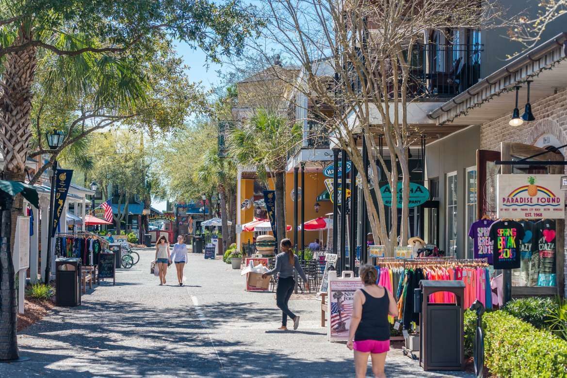 A street lined with shops and cafes, with pedestrians walking along.