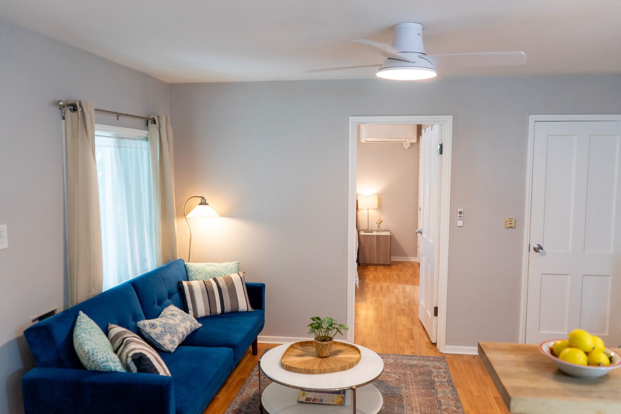 A living room with a blue sofa, a round coffee table, and a ceiling fan.