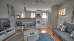 Una sala de estar moderna con sofá, televisor y zona de comedor.