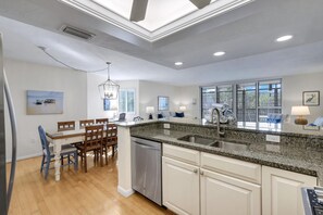Een moderne keuken met granieten aanrechtbladen, een inbouw vaatwasser en een eethoek met houten stoelen en een tafel.