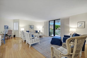 A spacious living room with a sofa, two armchairs, a coffee table, and a dining area with a table and chairs.