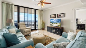 A living room with a large window, a ceiling fan, a TV, and a sofa set.